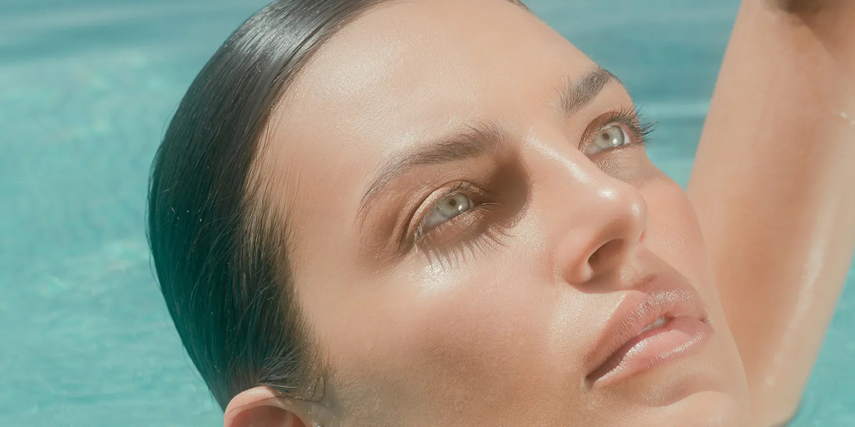 A radiant woman in a sunlit pool, showcasing the healthy aging and mitochondrial support